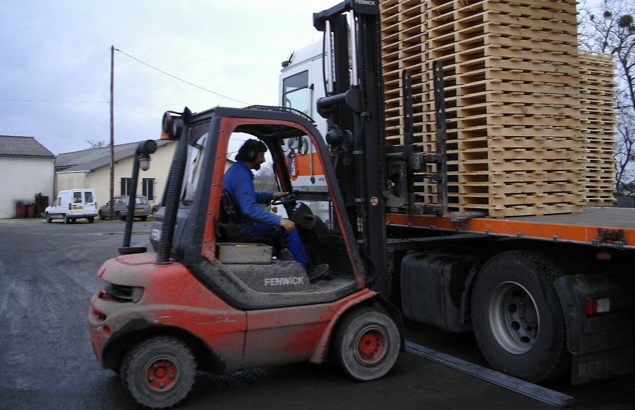 1280px-Chargement_de_camions_cariste